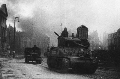 Französische Panzer auf dem Marktplatz. Für die Aufnahme einer französischen Wochenschau waren eine größere Zahl von Gebäuden im Stadtzentrum in Brand gesteckt worden. StadtAK 8/Alben 5, S. 697